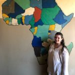 Image of EFSC student standing in front of the painted wall that has the content of Africa on it