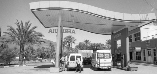 Black and white image of cars at a gas station