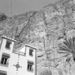Black and white image of tall wall of rock that looks up