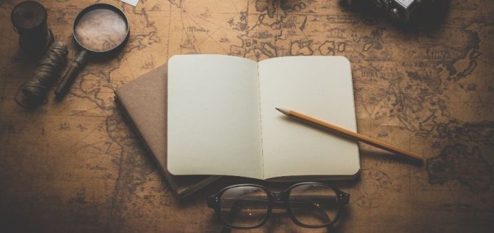 Open empty notebook with pencil laying inside it and glasses below it